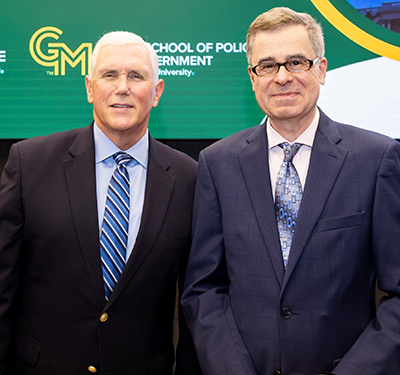Two men in jackets and ties smile at the camera.