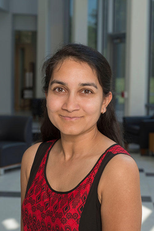 Smriti in a red shirt standing in the engineering building. 