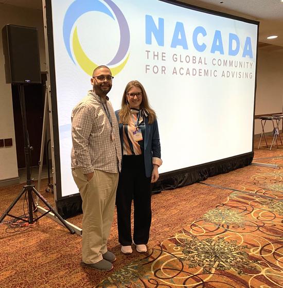 Joshua Fletcher and Barbara Snyder stand in front of a presentation screen that says NACADA: The Global Community for Academic Advising