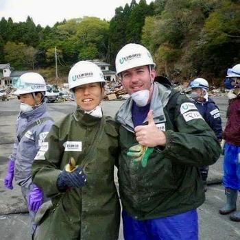 Two men in white hard hats give thumbs up to the camera.